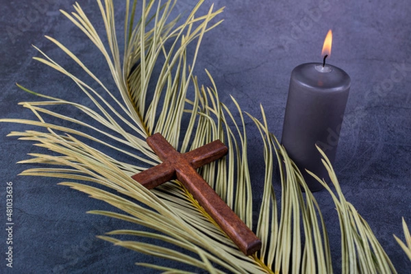 Fototapeta Catholic Cross with palm leaf and burning candle. Ash Wednesday, Lent season, Holy Week, Good Friday and Palm Sunday concept. Copy space.