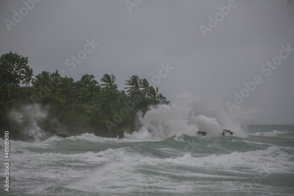 Fototapeta sea spray and surf on rocks in a storm with high waves on tropical cyclone