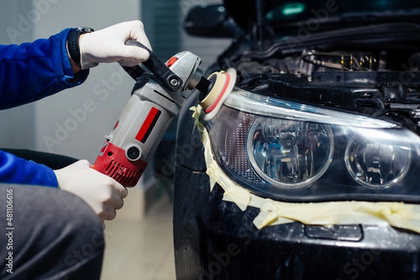 Fototapeta Car headlights cleaning with power buffer machine at car service