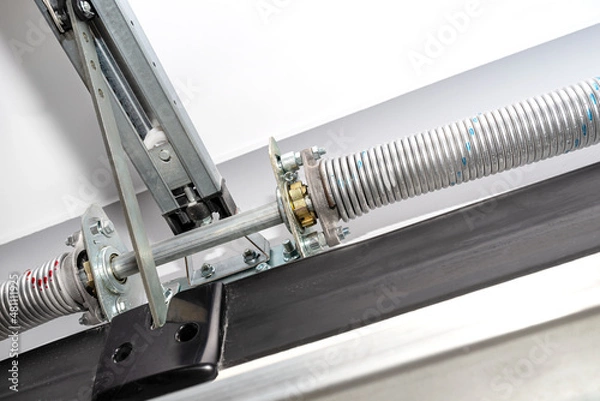 Obraz Springs tensioning the garage door mechanism, view from the inside, visible rail with chain and spring protection.
