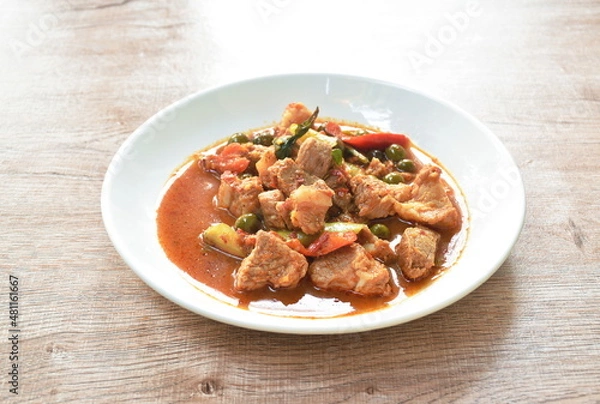Fototapeta spicy fried pork bone with eggplant in coconut milk curry on lettuce in plate