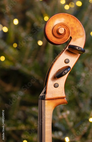 Fototapeta Pegbox of a cello on Christmas tree background.