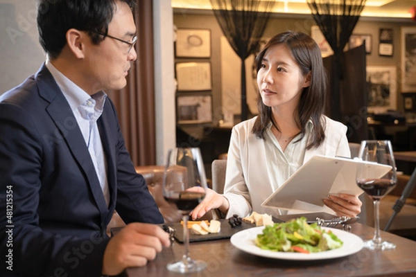 Obraz レストランの料理メニューのコンサルをする女性