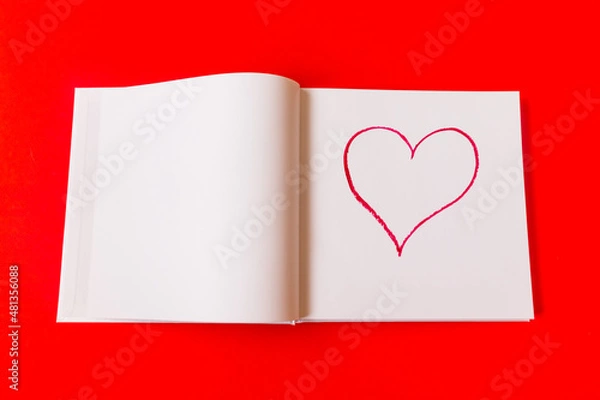Fototapeta Drawn heart in a notebook on a red background. Happy Valentine's Day. High quality photo