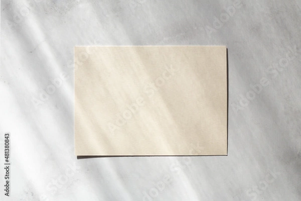 Fototapeta Blank paper sheet cards with sunlight shadows on stone background. Mockup scene with contrasting shadows