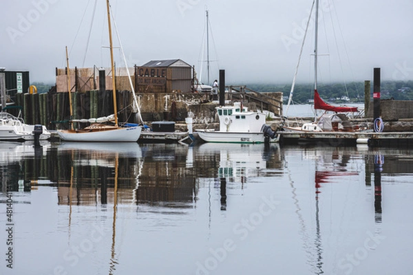 Fototapeta Small rustic harbor with sailboats in New England on cloudy day.