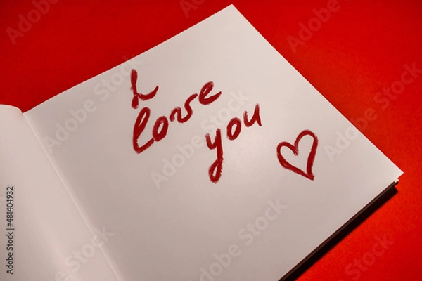 Obraz I love you. A declaration of love is written in lipstick on paper on a red background. Valentine's day card. High quality photo