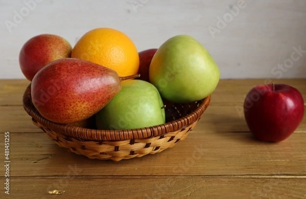 Obraz On the table is a wicker bowl with apples, pears and oranges.	
