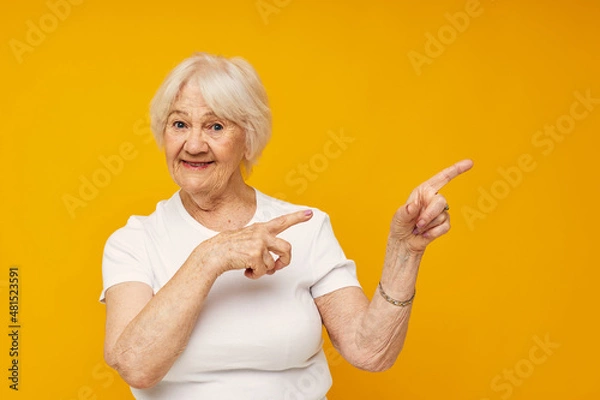 Fototapeta smiling elderly woman in casual t-shirt gestures with his hands cropped view
