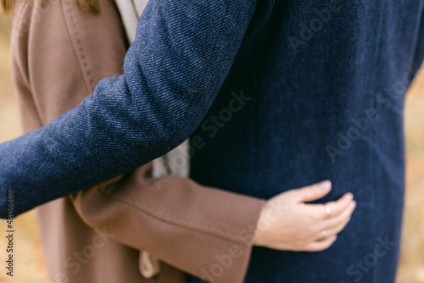 Fototapeta A couple of a girl and a man embracing each other in autumnal images. Dressed in stylish wool coats.