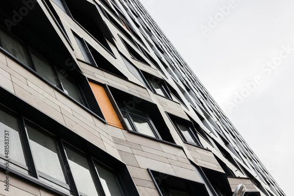 Fototapeta The exterior wall of a contemporary commercial style building with aluminum metal composite panels and glass windows. The futuristic building has engineered diagonal cladding frame panels.
