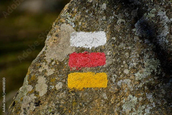 Obraz White, red and yellow signs for hikers on a stone of a path.