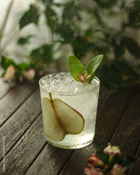 Fototapeta summer cocktail decorated with mint, lemon and slices pears on a wooden table on a floral background