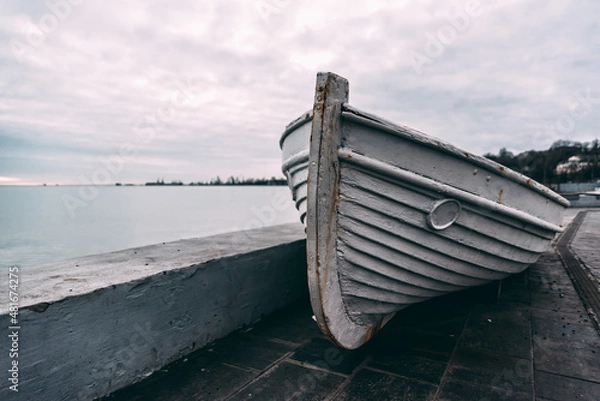 Obraz old wooden white boat on a concrete pier at sunset