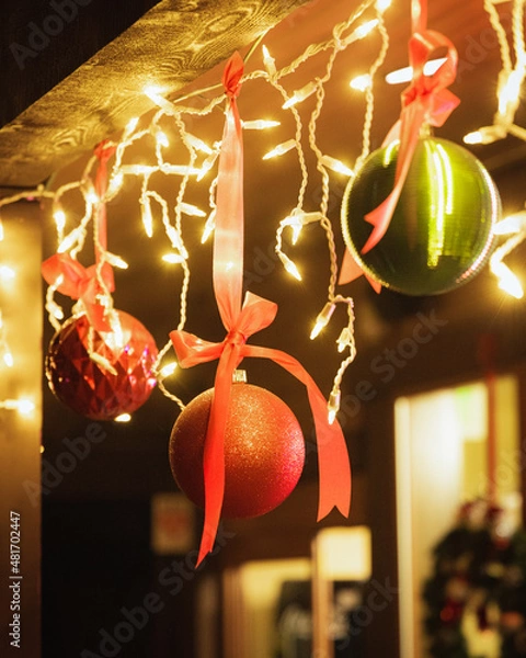 Fototapeta Ornaments and Christmas lights hanging from wooden beam
