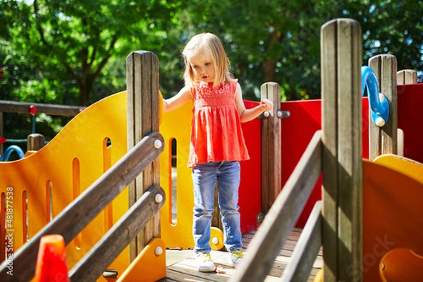 Fototapeta Girl on playground on a sunny day. Preschooler child playing on a slide. Outdoor activities for kids