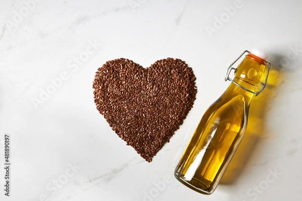 Obraz Top view of flaxseed formed into a heart shape next to a bottle of fish oil