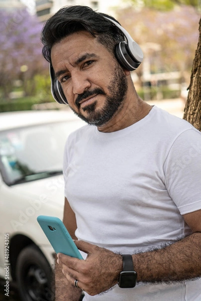 Fototapeta portrait of latin man with headphones in the city looking at camera