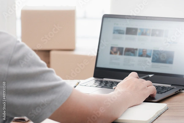 Fototapeta A man typing and search with important news on laptop in the internet on computer Compared to daily newspapers in office work
