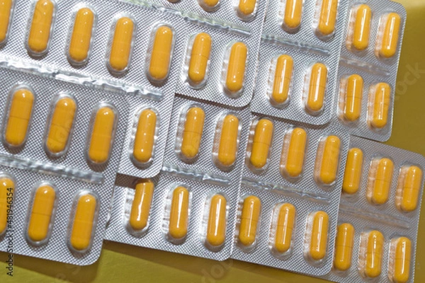 Obraz yellow capsules pills pills in a silver blister close-up