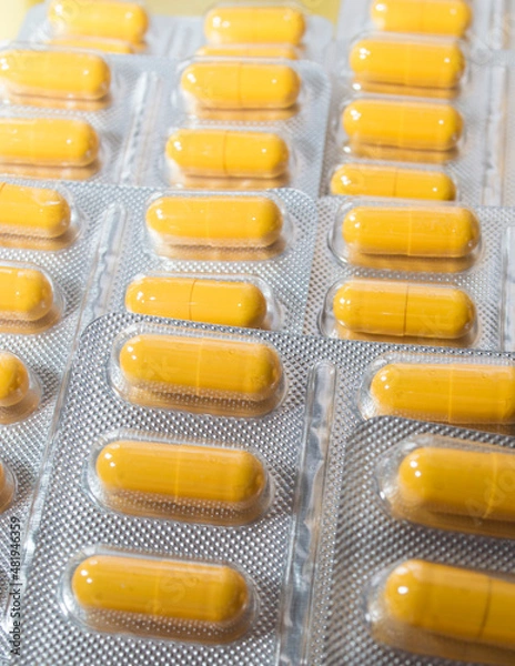 Obraz yellow capsules pills pills in a silver blister close-up