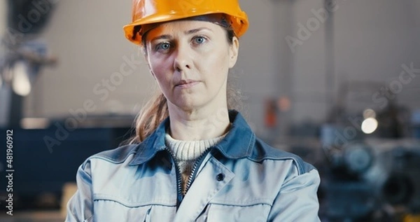 Fototapeta Portrait of a professional engineer - heavy industry worker in protective uniform and helmet. In the background, a large industrial plant