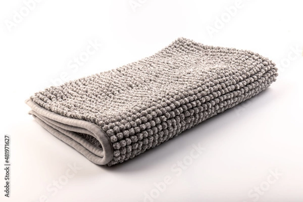 Fototapeta Soft grey bath mat against white background, closeup.Bath Accessories. Top view.