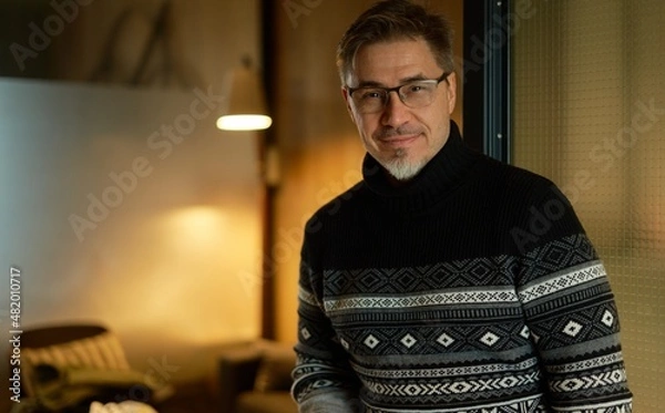 Fototapeta Happy man at home in scandinavian turtleneck sweater, smiling. Portrait of mature age, middle age, mid adult man in 50s wearing glasses.