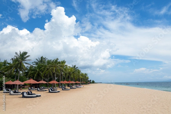 Obraz Empty beach with umbrellas and deck chairs. Palm trees. Beautiful summertime view seascape. Relax places island Bali island, Indonesia