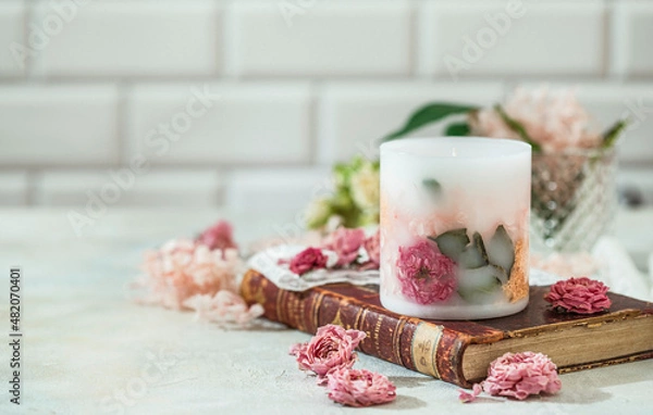 Fototapeta Handmade candles of a unique design, with different flowers, dry leaves on a light background. Candles made from organic wax, paraffin wax. Relaxation atmosphere. Luxurious lifestyle.