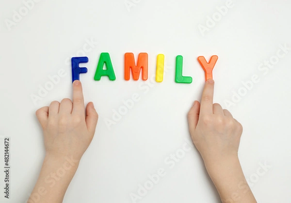 Fototapeta The child's hands and the word family made of multicolored letters
