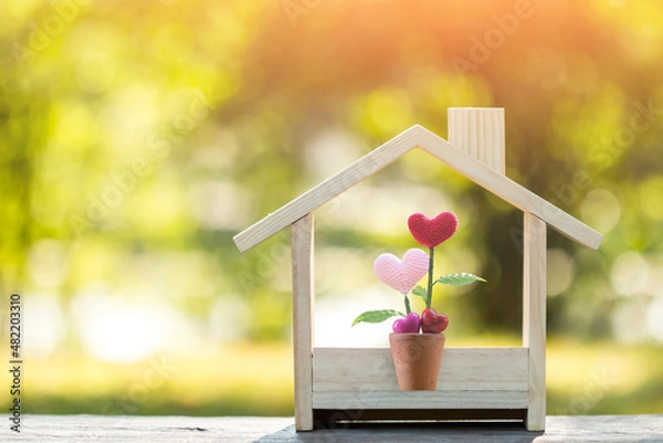 Obraz Flower of heart put in the wooden house model on sunlight in the public park, The buying a new real estate as a gift to family or the one loved concept.