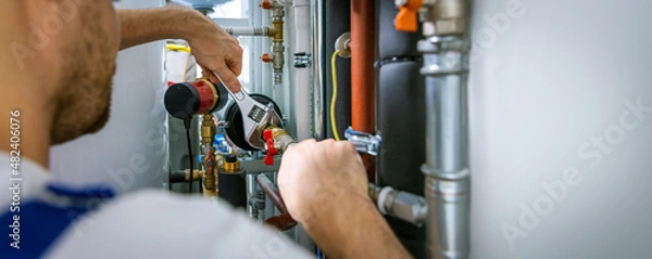 Fototapeta plumber working with wrench. screws the pipe fittings. banner copy space