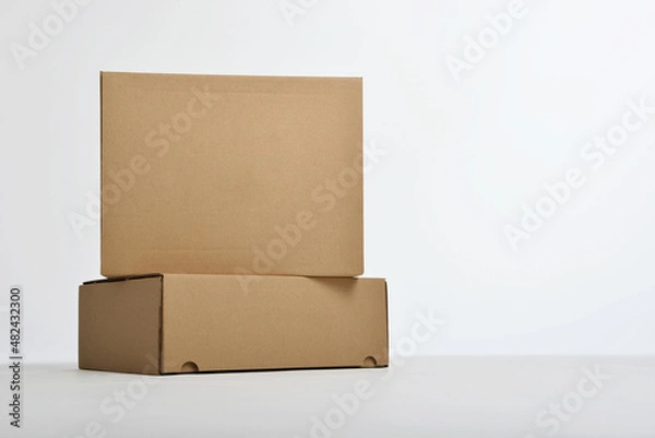Fototapeta Studio shot of two brown paper boxes. Boxes on white background. Packiging concept. Cardboard boxes.