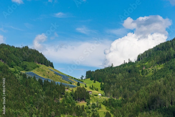 Obraz Photovoltaic, solar panels with alpine mountains in the background. Solar panels in country landscape over summer Alps is the innovation for sustainability of world solar energy.