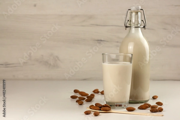 Fototapeta A bottle and a glass with alternative dairy free almond milk and nuts. Lactose free beverage