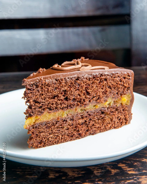 Fototapeta Chocolate Austrian dessert Sacher with apricot jam. One slice of traditional Sacher cake served on a white plate