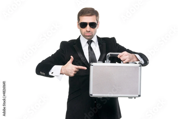 Fototapeta Stylish securuty guard pointing his finger on a metal suitcase.