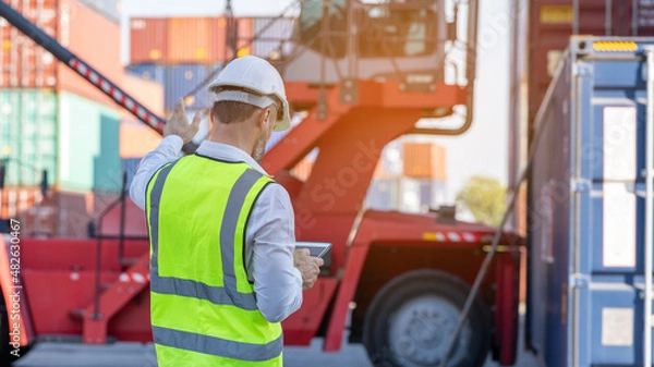Fototapeta CEO or Manager in white helmet with tablet control loading Containers box in warehouse , manager inspector or Safety Supervisor in Container CustomTerminal port concept import export transportation 