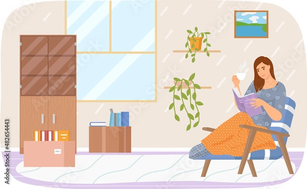 Fototapeta Cute young woman in chair reading book drinking tea. Home and beauty girl literature and information. Lady studying textbook. Person spends time rests in apartment with paper book and cup of hot drink