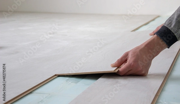 Obraz Workers' hands install a wooden laminate floor. Home renovation with wooden floors with measurements.