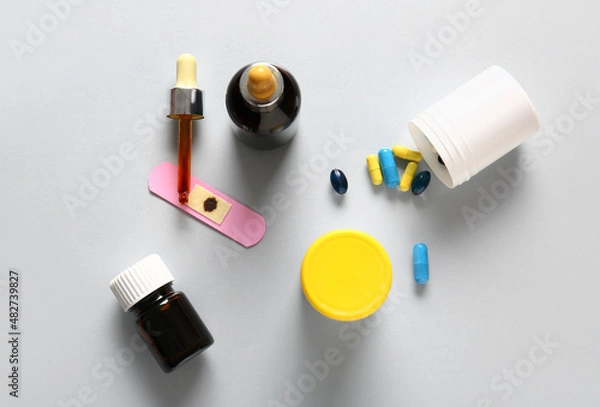 Fototapeta Bottles with iodine, medical plaster and pills on grey background