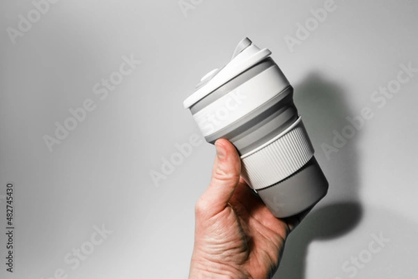 Obraz Reusable silicone cup for coffee in hand on a white background.