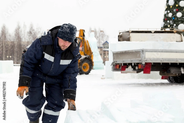 Obraz A worker loads ice blocks onto a sled