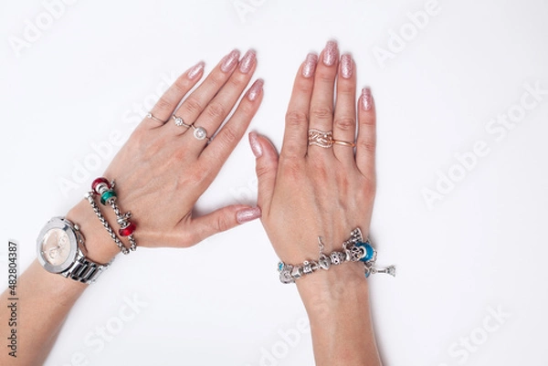 Fototapeta women's hands with manicure lie on a white background. on the hands rings, bracelets