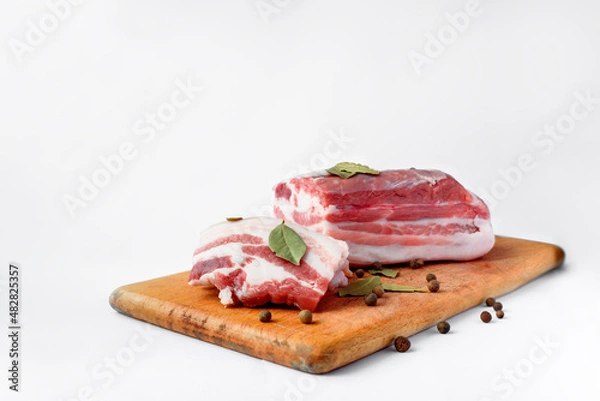Fototapeta bacon sliced on a wooden board with spices on a white background