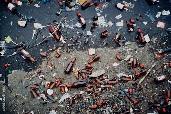 Fototapeta A large pile of household garbage on the sidewalk. Used glass bottles and paper packaging are lying on the ground