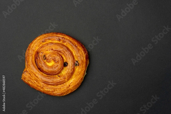 Fototapeta Delicious sweet roll with cinamon isolated on dark background