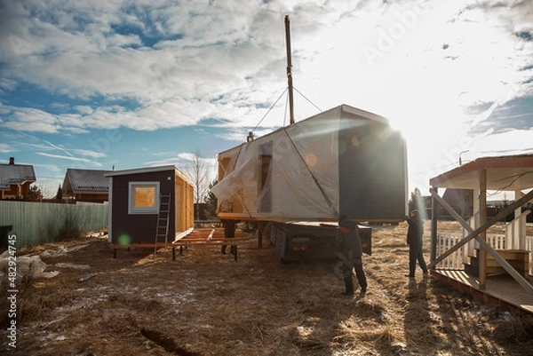 Fototapeta Delivery and installation of a modular frame house. Frame construction of small houses. Modular housing construction. Your house. An inexpensive house.