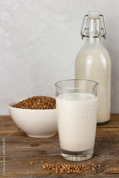 Fototapeta A bottle and a glass with alternative dairy free buckweat milk and seeds in a bowl. Lactose free beverage